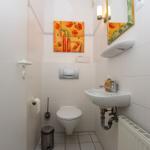 Badezimmer mit Toilette, Waschbecken und Wandbild mit Mohnblumen.