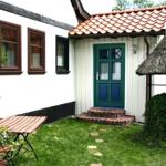 Haus mit grüner Tür, rotem Dach und Garten mit Tisch.
