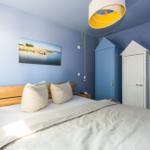 Schlafzimmer mit blauen Wänden, Bett, zwei Kleiderschränke und Wandbild.