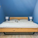 Schlafzimmer mit Holzbett, blauen Wänden und zwei Nachttischen mit Lampen.