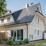 Ein Haus mit Dachgauben, Terrasse und Garten. Hausnummer 1b. Satellitenschüssel auf dem Dach.