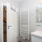 Badezimmer mit Dusche, Waschbecken und Heizkörper.