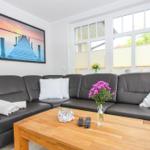 Ein Wohnzimmer mit einem dunklen Sofa, einem Holztisch und großen Fenstern.