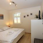 Schlafzimmer mit Bett, Fenster, TV und Wandbildern.