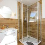 Bad mit Dusche, Waschbecken und Spiegel an Holzwand