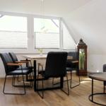 Essbereich mit Tisch, vier Stühlen und großem Fenster. Wohnbereich mit Sofa und Couchtisch.