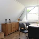 Esszimmer mit Holztisch, schwarzen Stühlen und Schrank an der Wand.