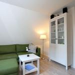 Ein Wohnzimmer mit grünem Sofa, weißem Tisch und Glaswand-Schrank.