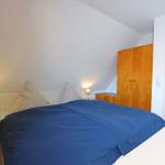 Schlafzimmer mit Bett, Nachttischen und Kleiderschrank unter Dachschrägen.