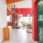 Haus mit Eingangstür, Treppe und Wohnbereich mit Sofa und Stuhl.