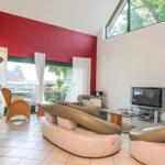 Wohnzimmer mit螺旋楼梯, Sofa, Fernseher und großem Fenster mit Blick auf Garten.