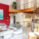 Wohnbereich mit roter Wand, Sofa, Couch und Küchenbereich mit Treppe.