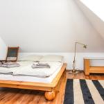 Schlafzimmer mit Holzbett, Schreibtisch und Fenster