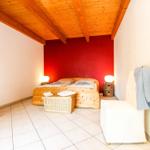 Schlafzimmer mit Holzbett, roter Wand, Körben und Holzboden.