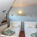 Zwei Einzelbetten in einem Dachzimmer mit Holzdecke und Wandspiegel.