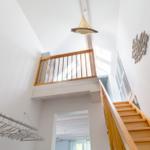 Haus mit Holztreppe, Balkon und Hängeschrank. Deckenleuchte und Wanddekoration sichtbar.