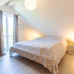 Schlafzimmer mit Dachschräge, Bett, Fenster, Nachttische und Deckenleuchte.