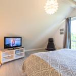 Schlafzimmer mit Bett, Fernseher und Fenster zur Terrasse.