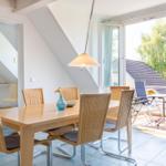 Esszimmer mit Tisch und Stühlen, Blick auf Balkon mit Garten.