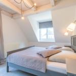 Schlafzimmer mit Doppelbett, Fenster und Holzbalkendecke.