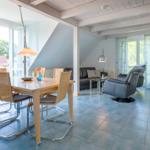 Essbereich mit Tisch und Stühlen. Wohnbereich mit Sofa und Sessel. Große Fenster und Terrasse.