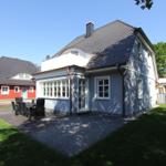 Haus mit Terrasse, Garten und Grillplatz. Nebenhaus und Garage sind sichtbar.