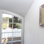 Blick durch Bogenfenster auf Balkon mit weißem Geländer und Garten