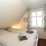 Schlafzimmer mit Doppelbett, Fenster und TV.