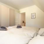 Schlafzimmer mit Doppelbett, KleiderSchrank und Bild an der Wand.
