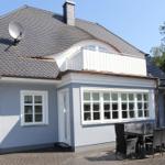 Ein Haus mit Balkon, Satellitenschüssel und Terrasse mit Tisch und Stühlen.