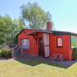 Rotes Ferienhaus mit Eingangstreppe, Fahrradständer und Garten. Holzterrasse und Kamin.
