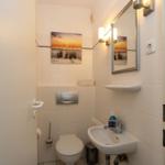 Badezimmer mit Toilette, Waschbecken und Spiegel an der Wand.