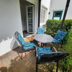 Terrasse mit runden Tisch und vier Stühlen mit blauen Kissen.