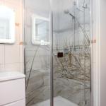 Badezimmer mit Dusche und Waschbecken. Duschwand hat Strandmotiv.