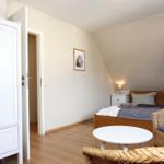 Schlafzimmer mit Bett, Kleiderschrank und Sitzgelegenheit.
