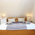 Schlafzimmer mit Doppelbett, zwei Nachttischen und Stehlampe.