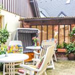 Terrasse mit Tischen, Stühlen und Pflanzen. Hinterhof mit Holzhaus und Kletterpflanzen.