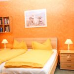 Schlafzimmer mit Doppelbett, Nachttischen und Wandbild. Wandfarbe orange.
