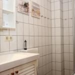 Badezimmer mit Waschbecken, Dusche und Wandbildern.