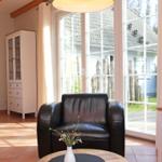 Ein Raum mit braunem Ledersofa, weißem Schrank und großen Fenstern zum Garten.