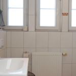 Badezimmer mit Waschbecken, Dusche und Fenstern.