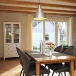 Esszimmer mit Holztisch, Stühlen und Glasvitrine. Fenster mit Blick auf Haus.
