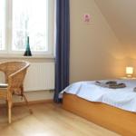 Schlafzimmer mit Bett, Stuhl und Fenster. Holzboden und Wand mit Dachneigung.