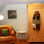 Ein Raum mit einem braunen Ledersessel, einem Holzschrank und einer Stehlampe.