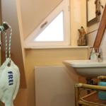 Badezimmer mit Waschbecken, Spiegel und Dachfenster. Tür mit FREI-Schild.