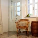 Bad mit Dusche, Bambusstuhl und Korb neben Fenster