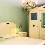 Schlafzimmer mit Bett, Kleiderschrank und Kronleuchter an der Decke.