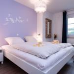 Schlafzimmer mit Bett, Nachttisch, Fenster und Wanddekoration.