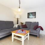 Wohnzimmer mit grauem Sofa, Couchtisch und Fernseher.