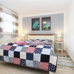 Schlafzimmer mit Bett, Fenster und zwei Nachttischen mit Lampen.